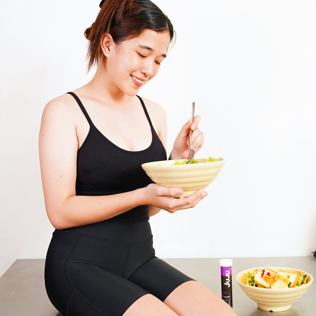 Woman eating with Juju slim container tube and food bowl beside her.