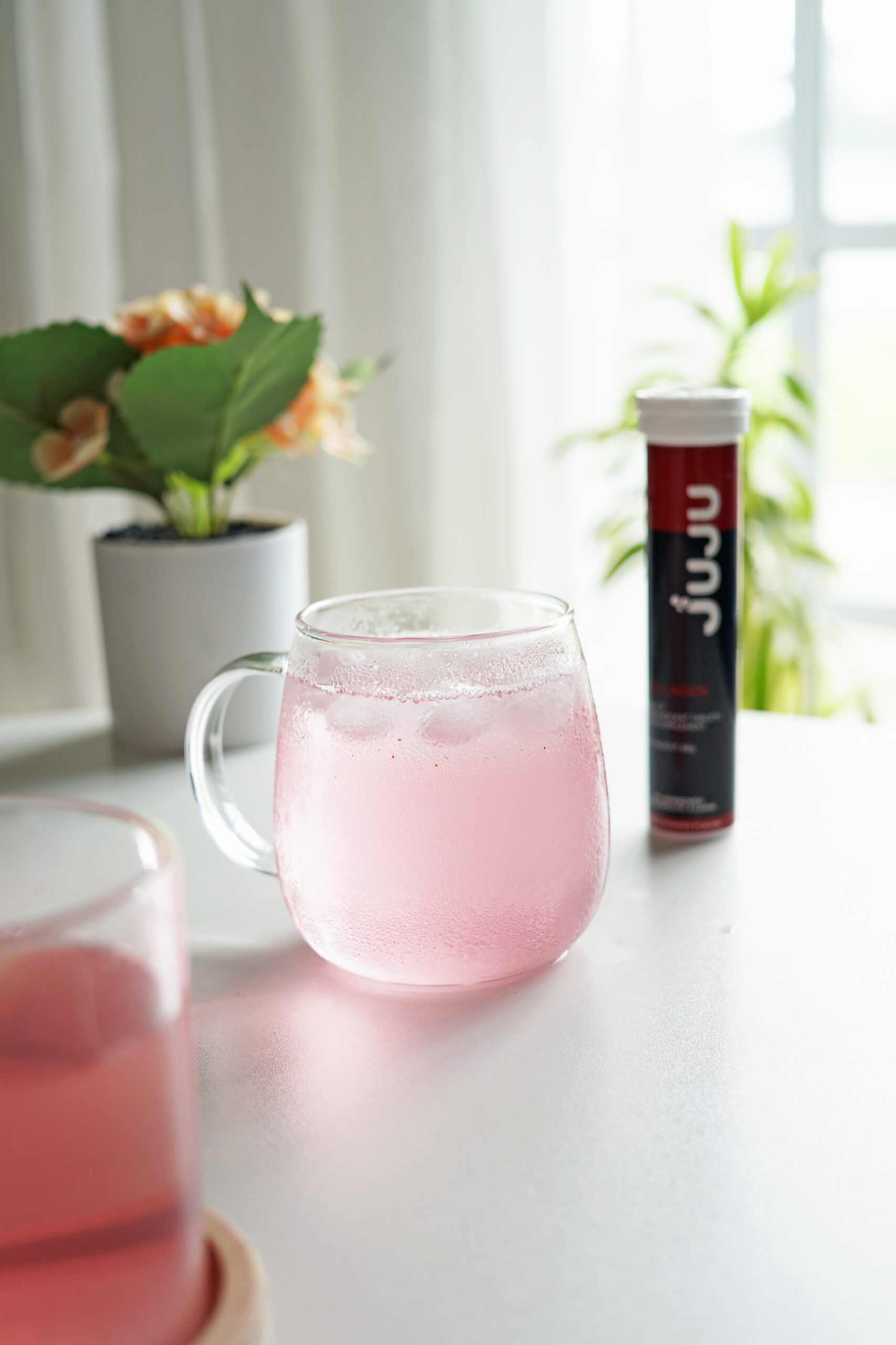 A glass with dissolve juju collagen with juju collagen tube container beside it.