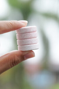 4 effervescent tablets held up in the air in blurred background.