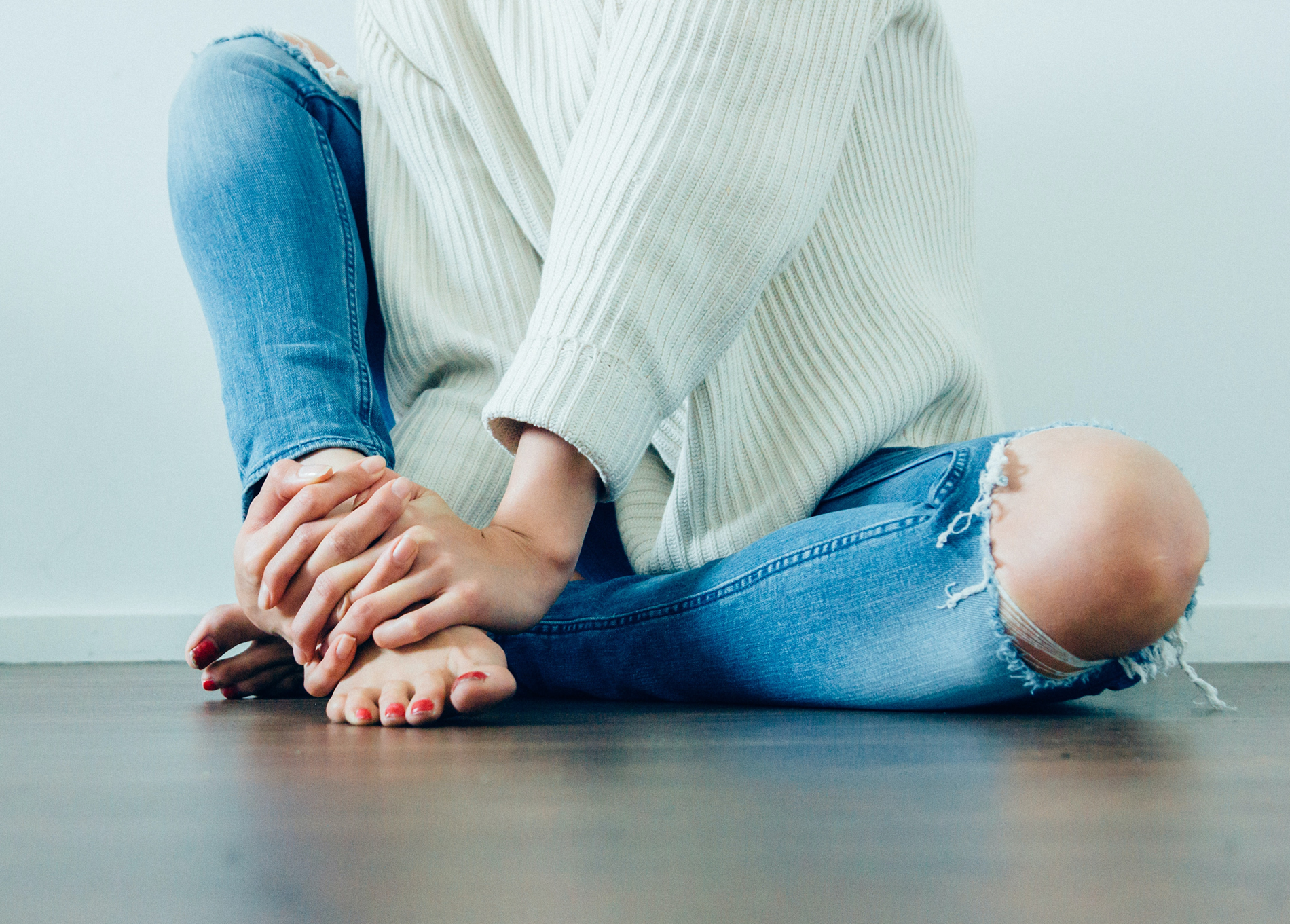 Woman sitting on the floor with her hands, toes and one knee exposed and posing for our collagen for skin whitening article.