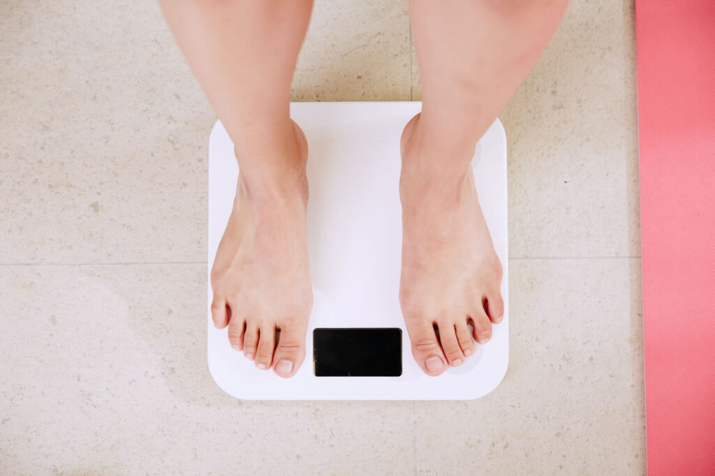 Person standing on a weighing scale for the post how can one maintain an ideal body weight